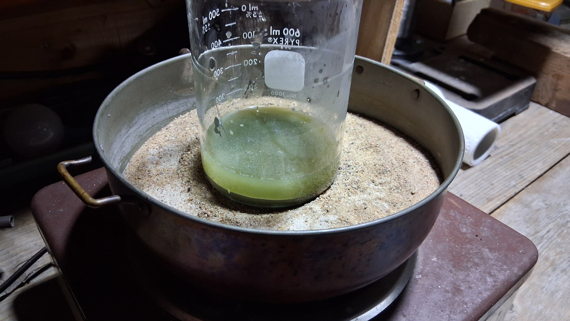 Le bécher au bain de sable sur la plaque : la solution verte se charge en métaux