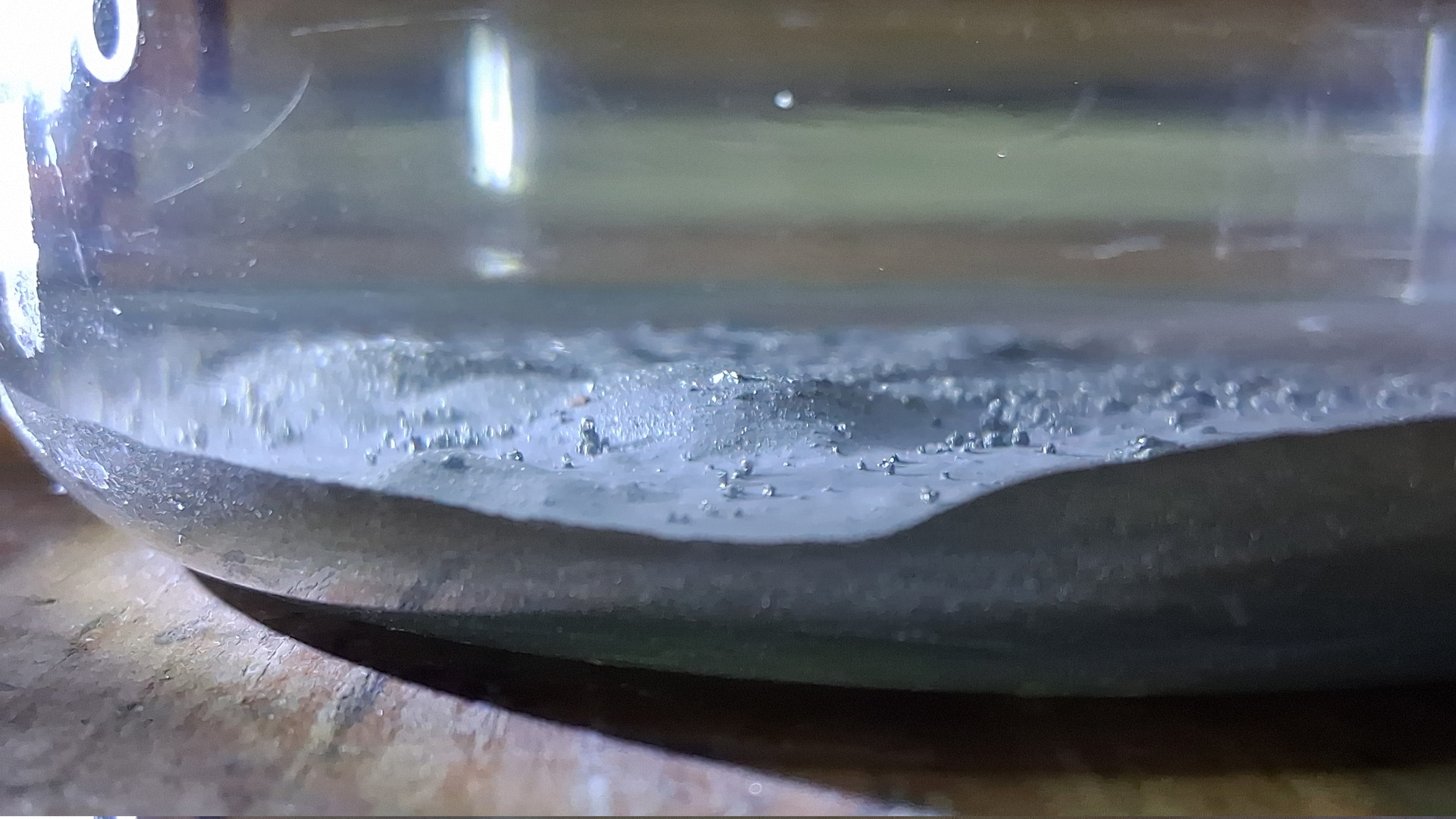 Le minerai dans l'acide, sans réaction visible : quelques bulles accrochées, aucune couleur